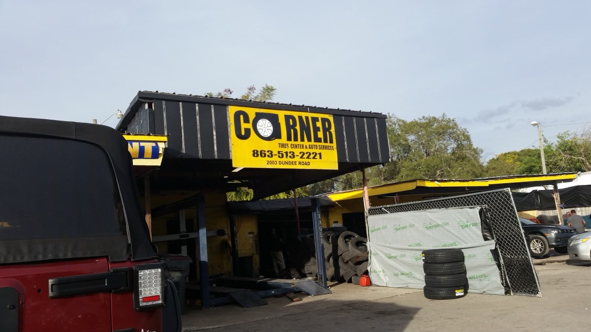 The yellow Corner Tires Center sign with its wheel logo, over the open service bay on Dundee Road